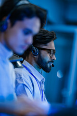 Professional call center agents with headsets providing friendly customer support. A dedicated male...