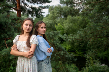 Fototapeta premium Portrait of beautiful young twin sisters in a summer forest.