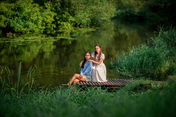 Portrait of beautiful young twin sisters in a summer forest.