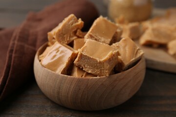 Homemade caramel candies in bowl on wooden table, closeup
