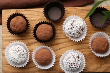 Delicious homemade candies with cocoa powder and coconut flakes on table, top view