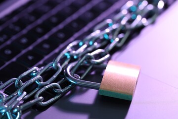 Cyber safety. Metal padlock with chain on laptop, closeup
