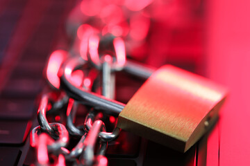 Cyber safety. Metal padlock with chain on laptop in color light, closeup