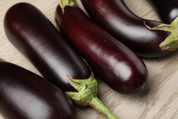 Many ripe eggplants on light wooden table, closeup