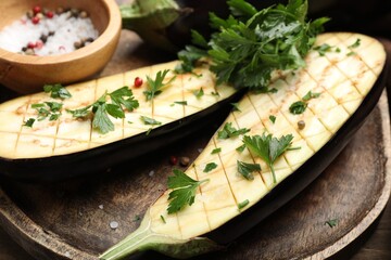 Halves of fresh eggplant, spices and parsley on wooden table, closeup