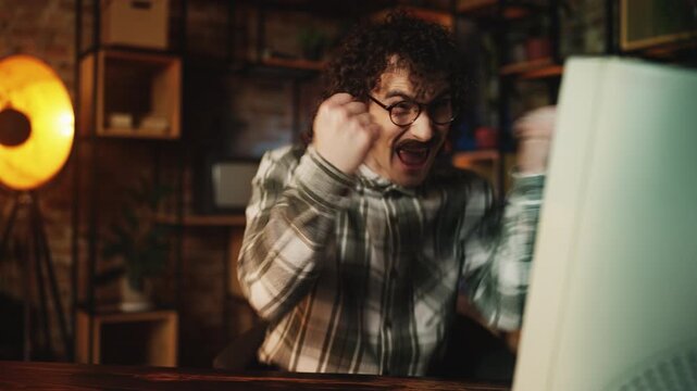 Funny male software tester working on computer and celebrating program launch