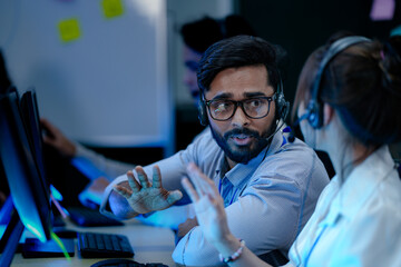 Call center agents collaborate on a difficult case. A male operator explains a complex solution to...
