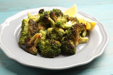 Tasty fried broccoli and lemon on light blue wooden table, closeup