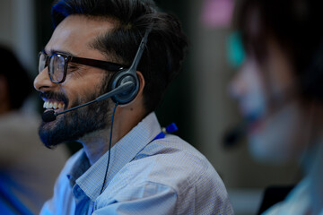 Close-up of a friendly male customer service agent smiling while talking on a headset. A concept...
