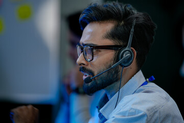 Close-up of a friendly male customer service agent smiling while talking on a headset. A concept...