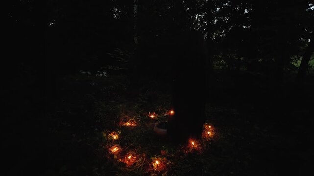 A witch walks in a circle of fire in a dark gloomy forest
