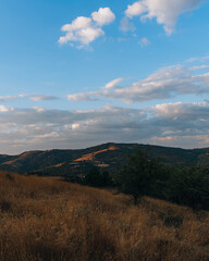 A beautiful mountain range with a clear blue sky. The sky is dotted with clouds, giving the scene a peaceful and serene atmosphere