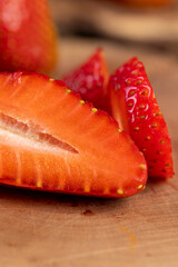 several sliced red ripe strawberries, ripe sweet and juicy strawberries cut into pieces on a wooden table