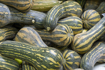 Pile of striped green and yellow squashes displayed at a market stall.