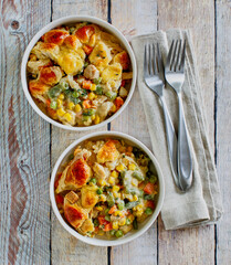 creamy chicken pot pie with onion, peas, and carrots topped with fresh thyme, one napkin