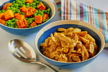simmered chicken thighs in brown gravy served with steamed carrots and peas