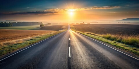 Fototapeta premium Asphalt road stretching towards a vibrant sunrise over a tranquil landscape of rolling hills and fields