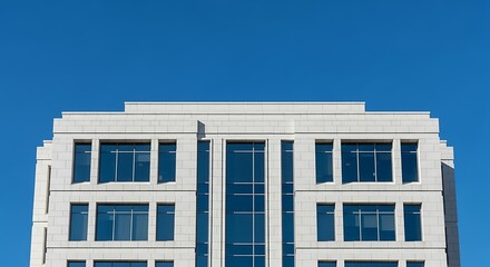 Close-up view of a modern white building with symmetrical windows against a clear blue sky.
