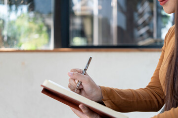 Young woman engages in note-taking at workspace.