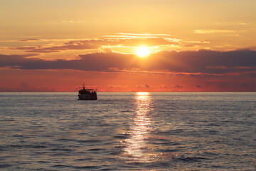 View of the horizon during sunset and a sea vessel on the horizon.
