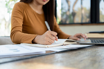 Young woman engages in note-taking at workspace.