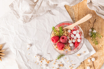 An overhead shot of a single glass of layered raspberry and chia seed pudding with fresh...