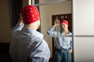 Woman wearing red bandana and striped shirt reflecting in mirror, concept of self-acceptance,...