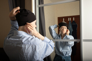 Woman looking at her reflection in mirror at home, casual fashion style with bandana, concept of...