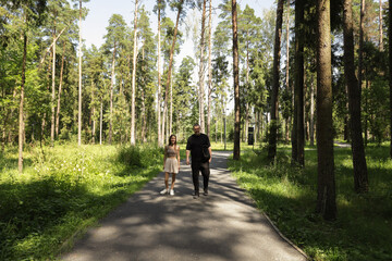 Obraz premium Couple Walking Together on Forest Trail in Summer,Relaxed Outdoor Lifestyle, Nature and Romance Scene