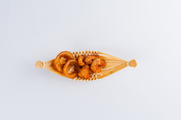 Crispy fried pork rinds in a small woven basket on a white background. Overhead studio shot.