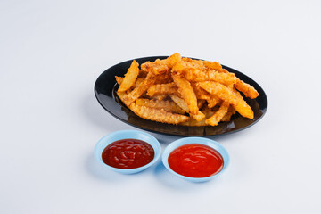 Crispy golden french fries served on a black plate with two small bowls of red sauce. White background.