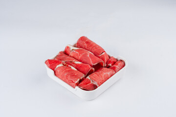 Thinly sliced raw beef arranged in a small white square container against a white background. The beef is a rich red color.