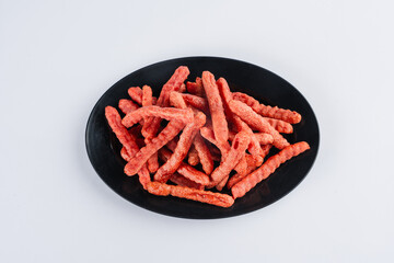 Red, crispy snacks on a black plate, overhead shot. A simple, appetizing image of a food product.