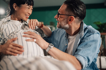 Loving couple holding pregnant belly at home