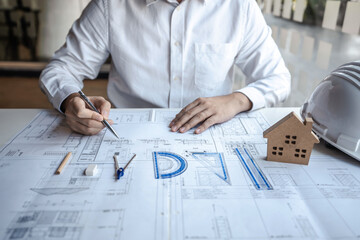 Architects or engineering working on objects tools and construction planning new architectural project on blueprint and model house in modern office