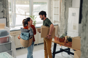 Happy couple carrying boxes and entering new home