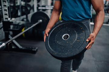 Bodybuilder carrying weight plate in gym for strength training workout