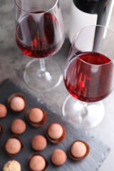 Tasty truffle bonbons and red wine on grey table, selective focus