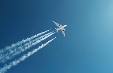 Twin engined jet liner flies high in deep blue sunny sky leaving white contrails. Aircraft cruises smoothly above clouds on clear day. Airplane travels on international journey. Global business