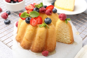 Tasty Bundt cake with berries, honey and mint on light grey table, closeup