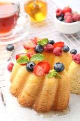 Tasty Bundt cake with berries, honey, mint and tea on table, closeup