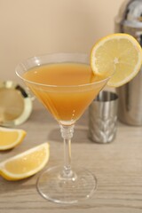 Tasty lemon cocktail in glass and bartender equipment on wooden table, closeup