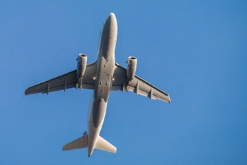 Modern airplane soars overhead against a clear blue sky perfect for travel and transportation themes