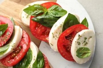 Delicious sandwiches with mozzarella cheese, tomatoes and basil on light grey table, closeup