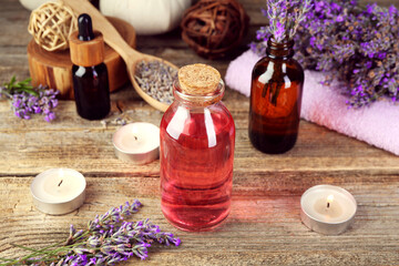 Lavender essential oil, flowers, candles and towel on wooden table
