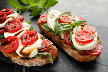 Delicious sandwiches with mozzarella cheese, tomatoes and basil on table, closeup