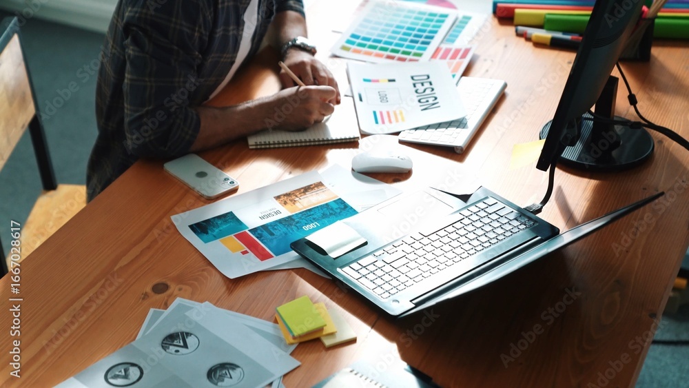 Poster interior designer looking at laptop and designing color while looking at palette at meeting table wi
