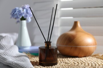 Spa composition with reed air freshener on wicker mat indoors, closeup
