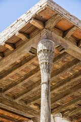 Detail of a wooden column and raw timber ceiling in a historic palace in Khiva, Uzbekistan