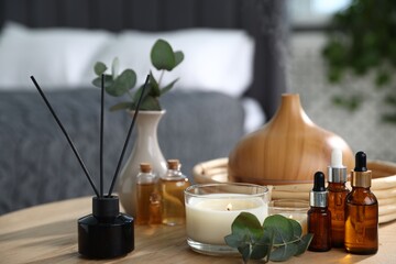 Spa composition with aroma oil diffuser, reed air freshener and burning candles on wooden table...